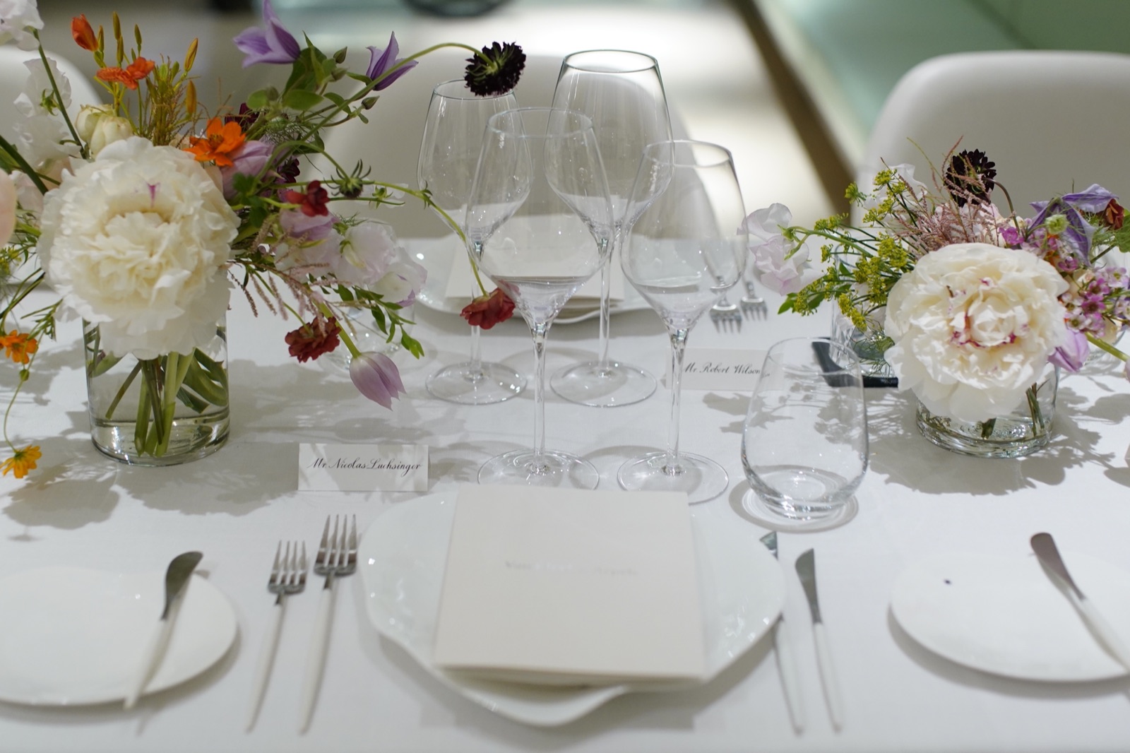 Intimate candlelit yacht dinner table — glasses, flowers, warm candlelight on linen